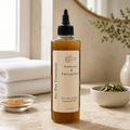 Bottle of 'Ambunu & Fenugreek' pre-poo treatment on a wooden surface with natural elements.